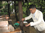 鳩森八幡神社の手水舎にて、手を清める中矢先生。